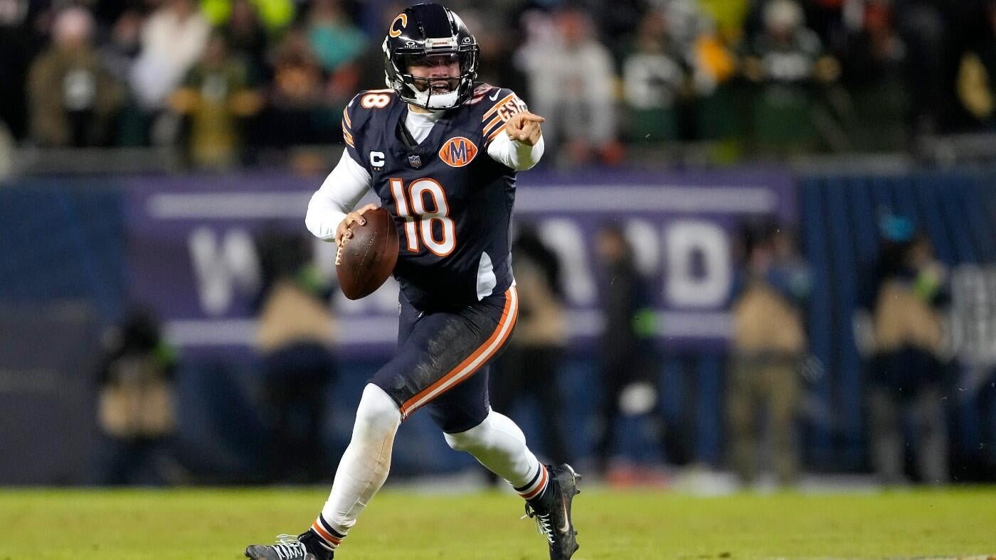 Chicago Bears quarterback #18, wearing a navy jersey and helmet, drops back to pass while pointing downfield during an NFL game.